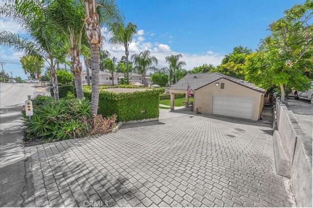 exterior space with fence, an attached garage, stucco siding, decorative driveway, and a tiled roof