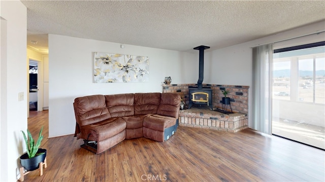 living room with a textured ceiling, a wood stove, and wood finished floors