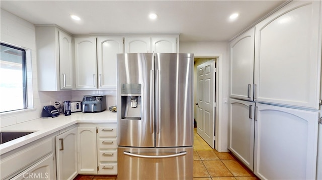 kitchen featuring white cabinetry, recessed lighting, stainless steel fridge, light countertops, and light tile patterned floors