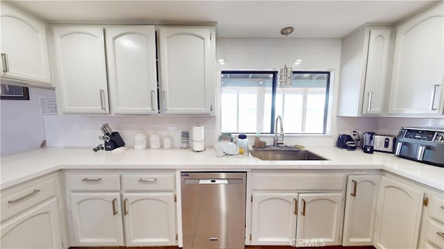 kitchen featuring a sink, stainless steel dishwasher, light countertops, and white cabinetry