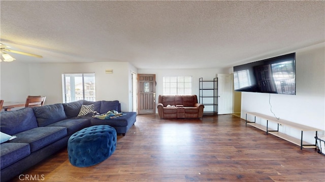 living area with ceiling fan, a textured ceiling, and wood finished floors