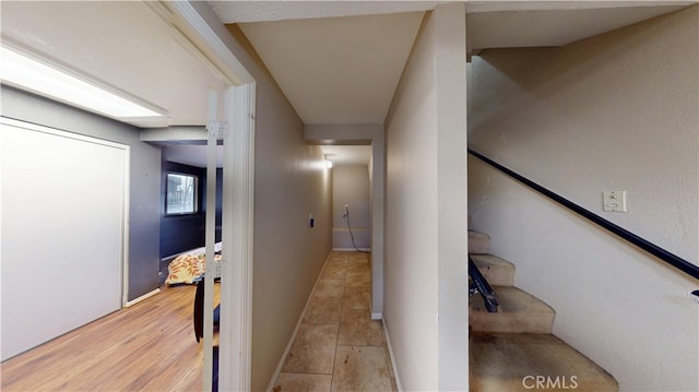 hallway featuring light wood-type flooring, stairs, and baseboards