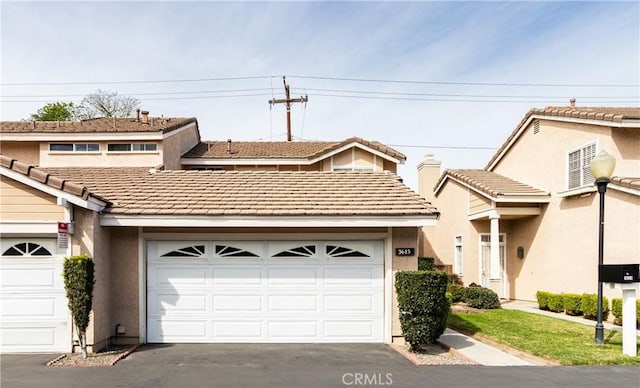 multi unit property with driveway, an attached garage, and stucco siding