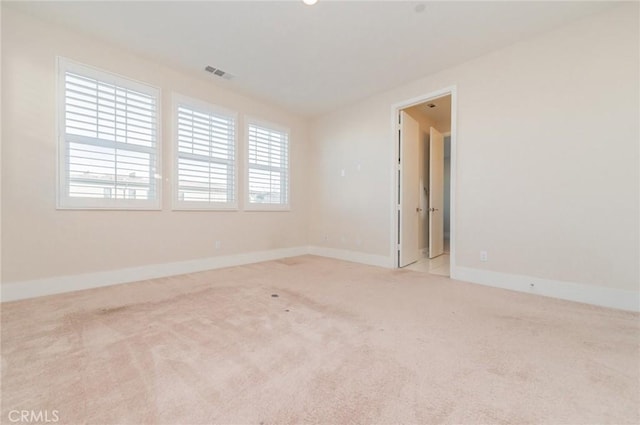 spare room featuring carpet, visible vents, and baseboards