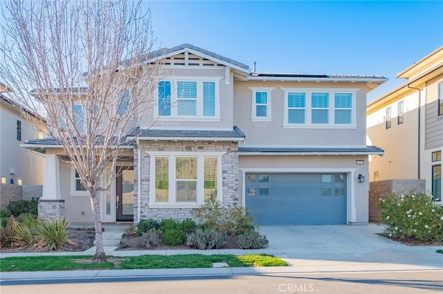 craftsman-style house with stucco siding, an attached garage, roof mounted solar panels, stone siding, and driveway