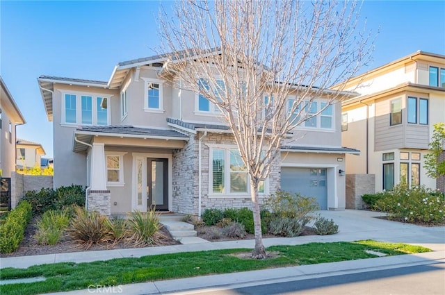 view of front of property with an attached garage, stone siding, concrete driveway, and stucco siding