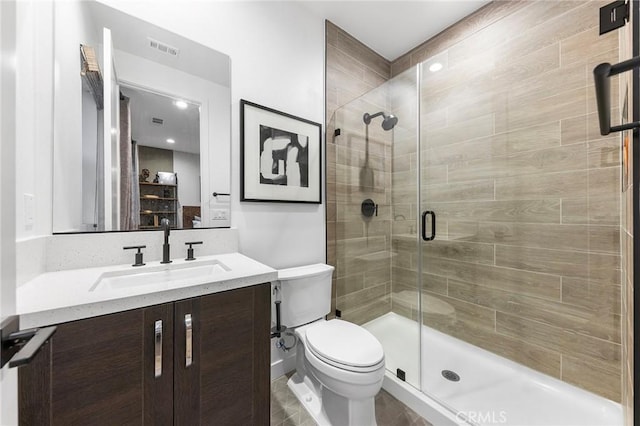 bathroom with toilet, a shower stall, visible vents, and vanity