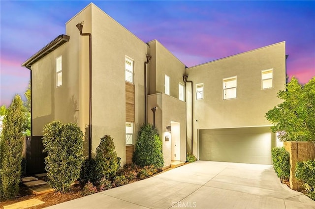 view of front of home with an attached garage, concrete driveway, and stucco siding