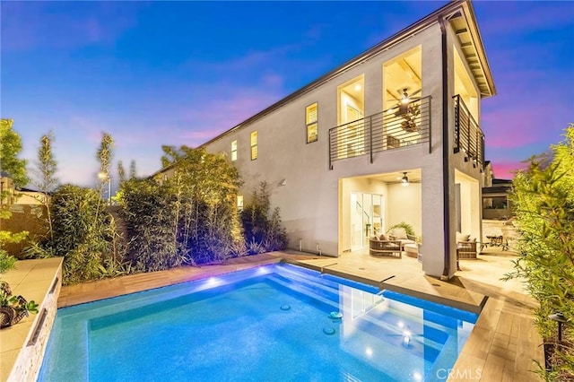 rear view of property with a patio, a balcony, an outdoor hangout area, a pool, and stucco siding