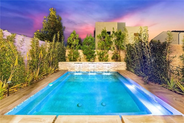 pool at dusk featuring a fenced backyard