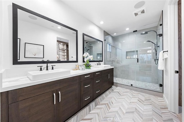 full bathroom featuring double vanity, a stall shower, a sink, and recessed lighting