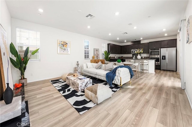 living area with baseboards, recessed lighting, visible vents, and light wood-style floors