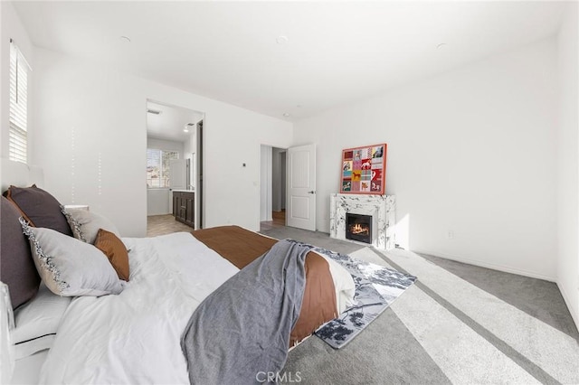 carpeted bedroom with connected bathroom and a fireplace