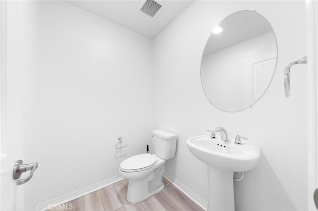 bathroom with baseboards, a sink, toilet, and wood finished floors