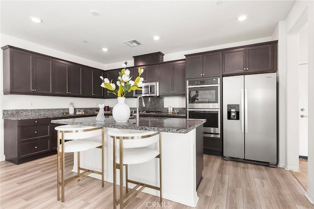 kitchen featuring dark brown cabinetry, visible vents, appliances with stainless steel finishes, and light wood-style flooring