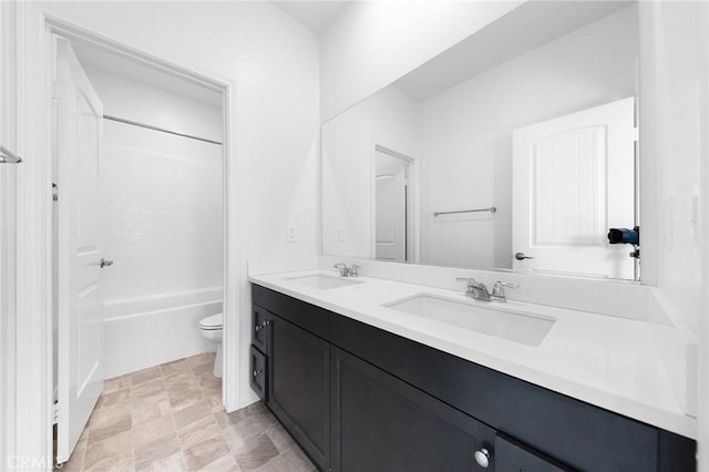 bathroom featuring double vanity, toilet, a sink, and bathing tub / shower combination