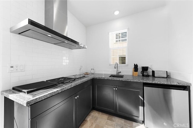 kitchen featuring tasteful backsplash, refrigerator, wall chimney range hood, stainless steel gas cooktop, and a sink