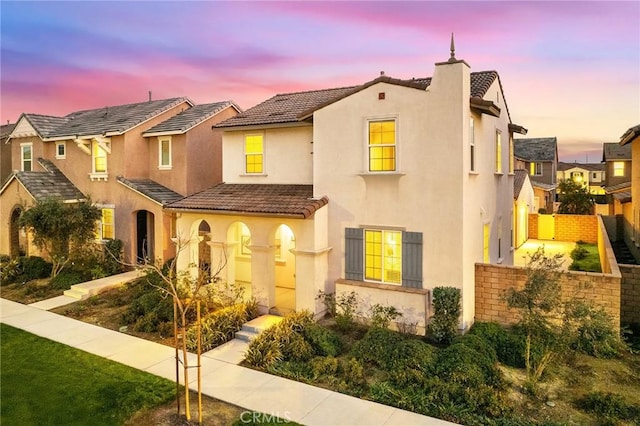 mediterranean / spanish home with a tiled roof, a chimney, fence, and stucco siding