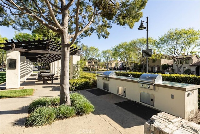 view of patio / terrace with area for grilling, an outdoor kitchen, a pergola, and a sink