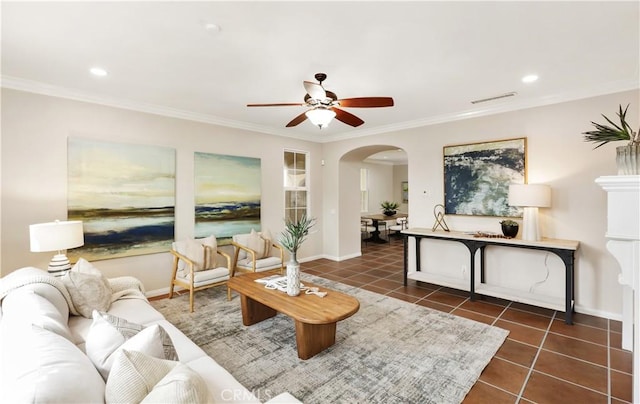 living room with arched walkways, tile patterned flooring, a ceiling fan, ornamental molding, and baseboards