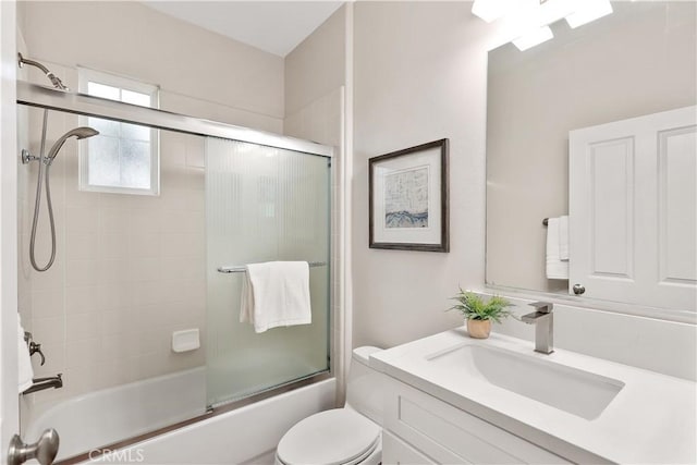 bathroom featuring combined bath / shower with glass door, vanity, and toilet