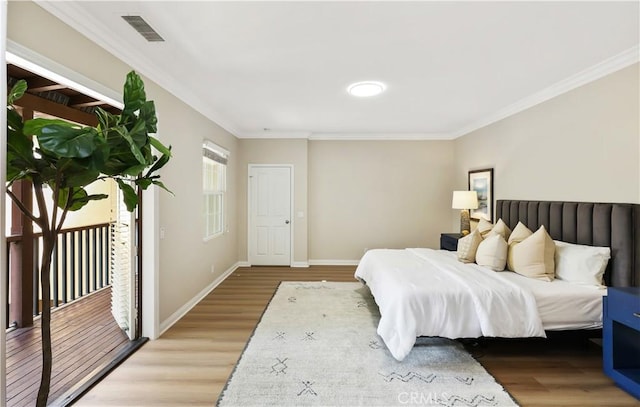 bedroom featuring wood finished floors, ornamental molding, baseboards, and access to outside