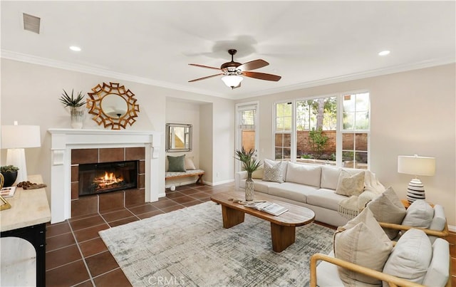 living room with visible vents, ornamental molding, dark tile patterned flooring, baseboards, and a tile fireplace