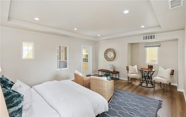 bedroom with visible vents, a tray ceiling, and wood finished floors