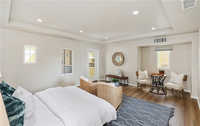 bedroom featuring a raised ceiling, wood finished floors, recessed lighting, and baseboards