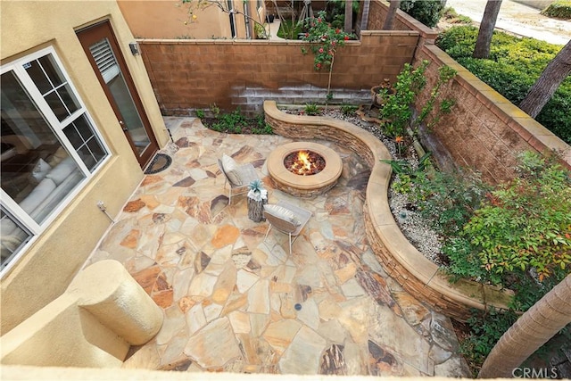 view of patio with an outdoor fire pit and fence