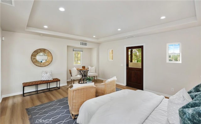 bedroom with a raised ceiling, recessed lighting, wood finished floors, and baseboards