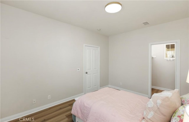 bedroom featuring visible vents, a closet, baseboards, and wood finished floors