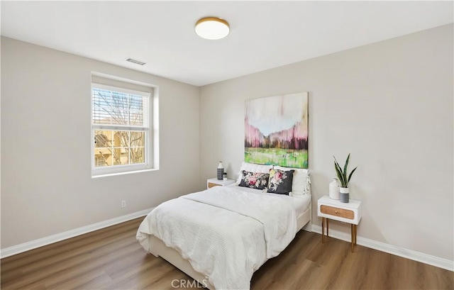 bedroom featuring visible vents, baseboards, and wood finished floors