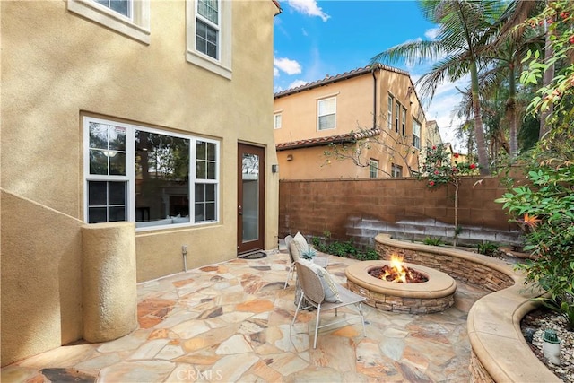 view of patio with an outdoor fire pit and fence
