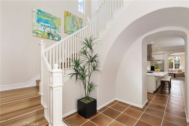 stairs with a high ceiling, wood finished floors, and baseboards