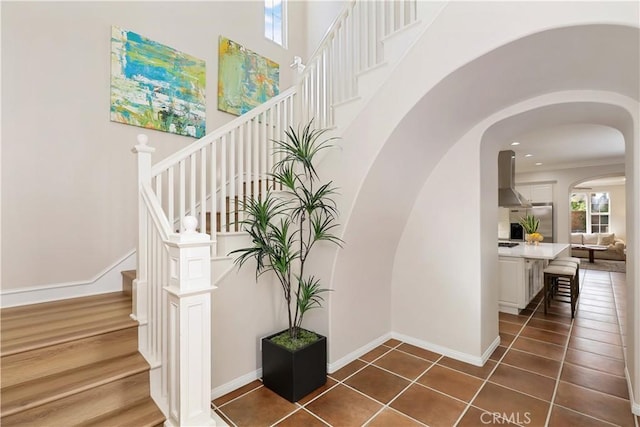 stairway featuring tile patterned floors, baseboards, arched walkways, and recessed lighting
