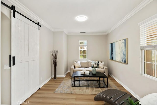 living room with a barn door, crown molding, baseboards, and wood finished floors