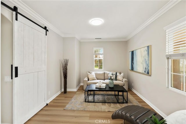 living area featuring a barn door, wood finished floors, crown molding, and baseboards