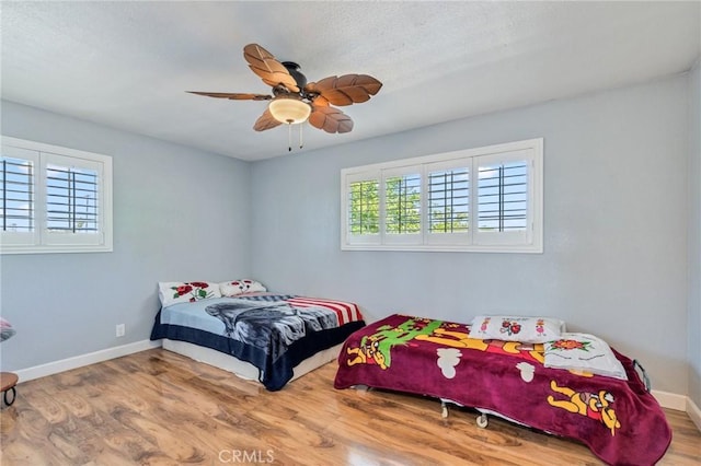 bedroom with a ceiling fan, baseboards, and wood finished floors