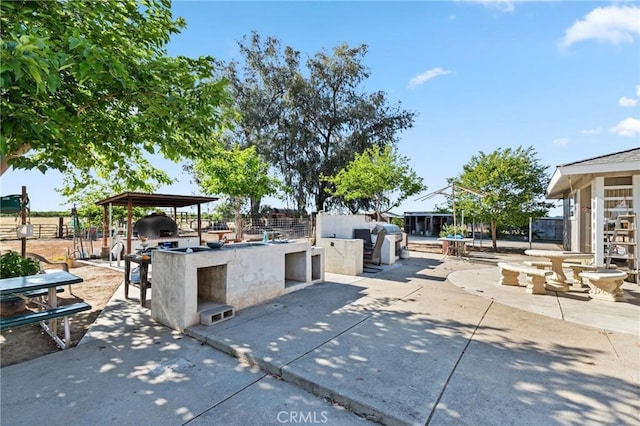 view of patio / terrace featuring fence, outdoor dry bar, and exterior kitchen