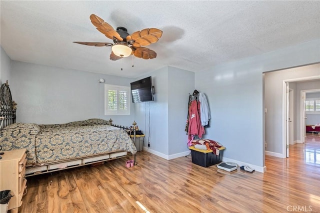 bedroom with a textured ceiling, multiple windows, and wood finished floors