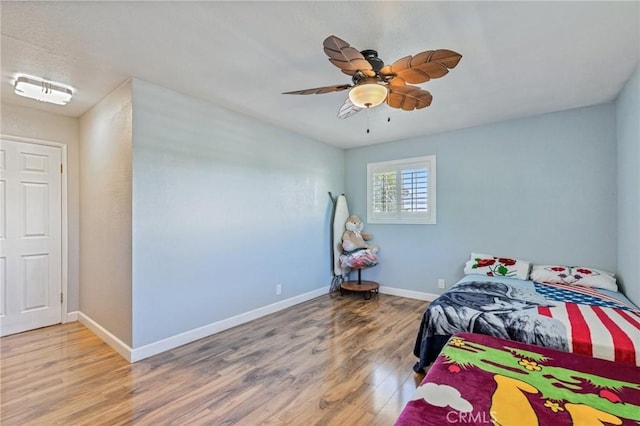 bedroom featuring light wood finished floors, baseboards, and a ceiling fan