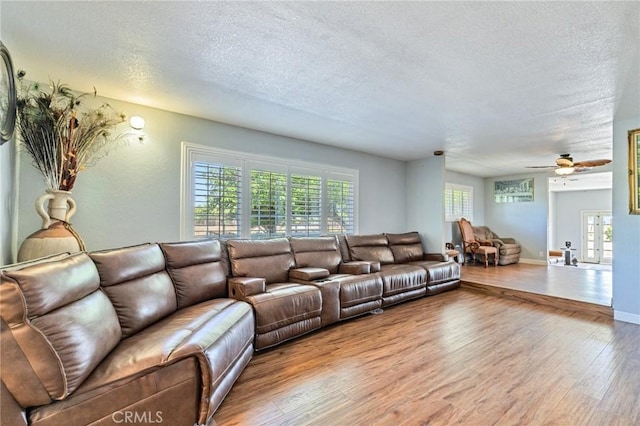 living room with a textured ceiling, baseboards, wood finished floors, and a healthy amount of sunlight