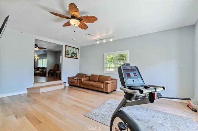 exercise room featuring ceiling fan, light wood finished floors, visible vents, and baseboards