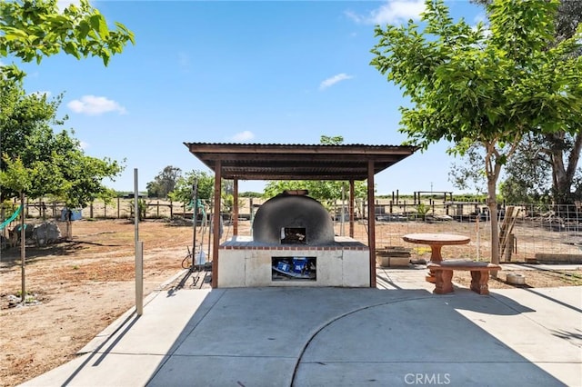 view of patio featuring an outdoor brick fireplace and fence