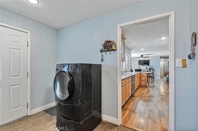 laundry area with a sink, baseboards, washer / clothes dryer, and wood finished floors