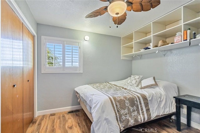 bedroom featuring baseboards, a ceiling fan, wood finished floors, a textured ceiling, and a closet