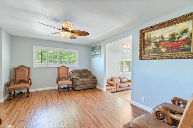 sitting room featuring wood finished floors, a ceiling fan, and baseboards