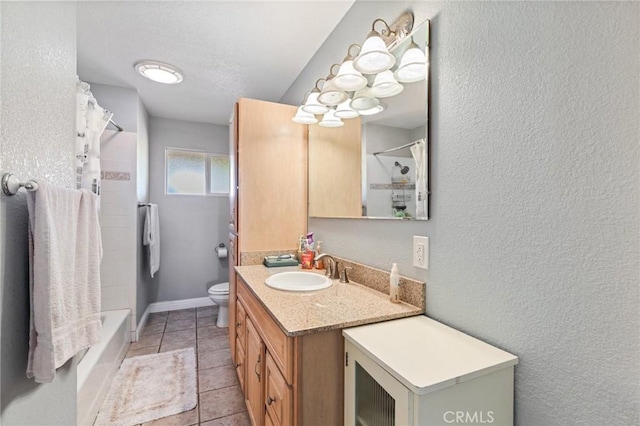 full bathroom featuring baseboards, a textured wall, toilet, tile patterned floors, and vanity