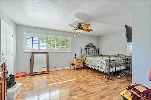 bedroom featuring a textured ceiling, wood finished floors, and baseboards